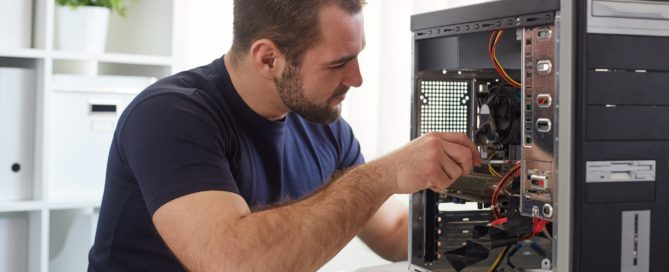 Young man repairing computer while sitting at his working place